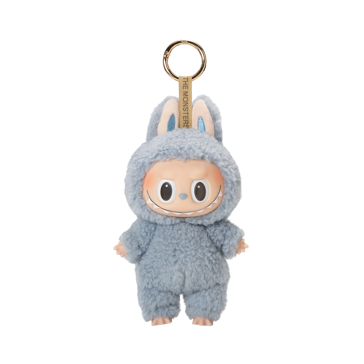 A fluffy light blue plush toy keychain of a character with a wide, mischievous smile, large black eyes, and bunny ears with blue glitter inside, with the text "THE MONSTERS" on the keyring strap.