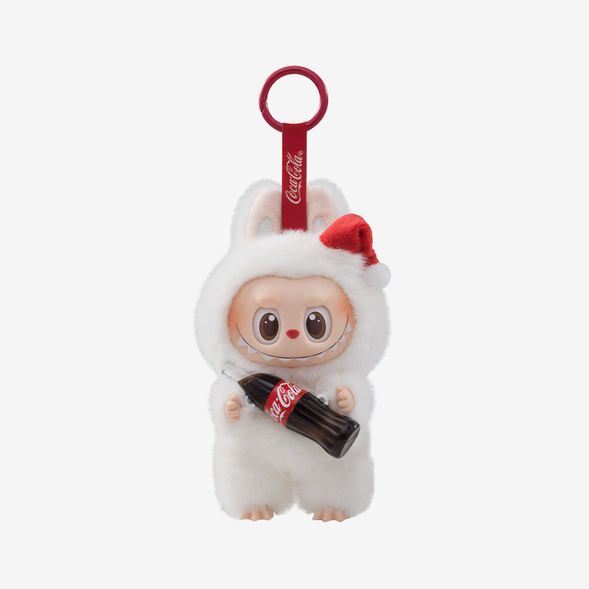 A collectible keychain figure from the Pop Mart x Coca-Cola collaboration, part of "The Monsters" Vinyl Face blind box series. The character is dressed in a fluffy white bunny costume with a red Santa hat and bunny ears. It has a cute, wide-eyed expression with a mischievous grin, and is holding a miniature Coca-Cola bottle. The keychain strap is red with the Coca-Cola logo printed on it, matching the festive holiday theme.
