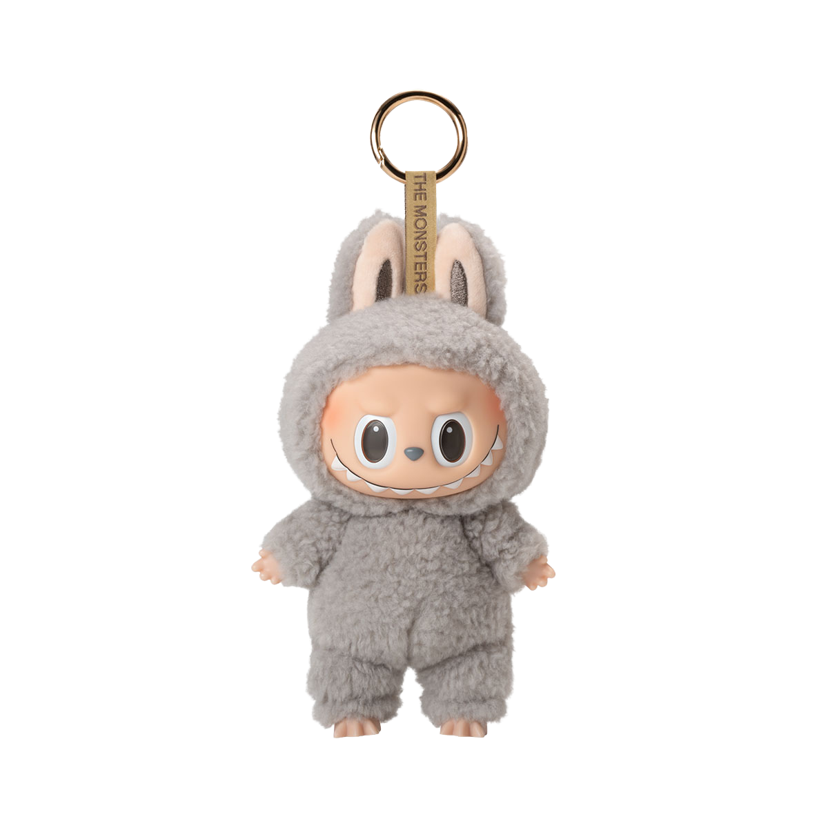A fluffy gray plush toy keychain of a character with a wide, mischievous smile, large black eyes, and bunny ears, with the text "THE MONSTERS" on the keyring strap.