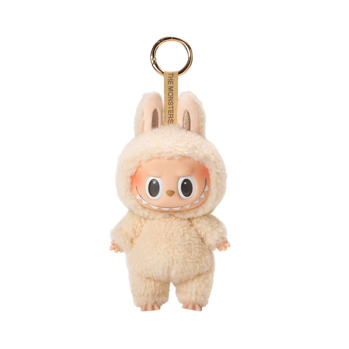 A fluffy cream-colored plush toy keychain of a character with a wide, mischievous smile, large black eyes, and bunny ears, with the text "THE MONSTERS" on the keyring strap.