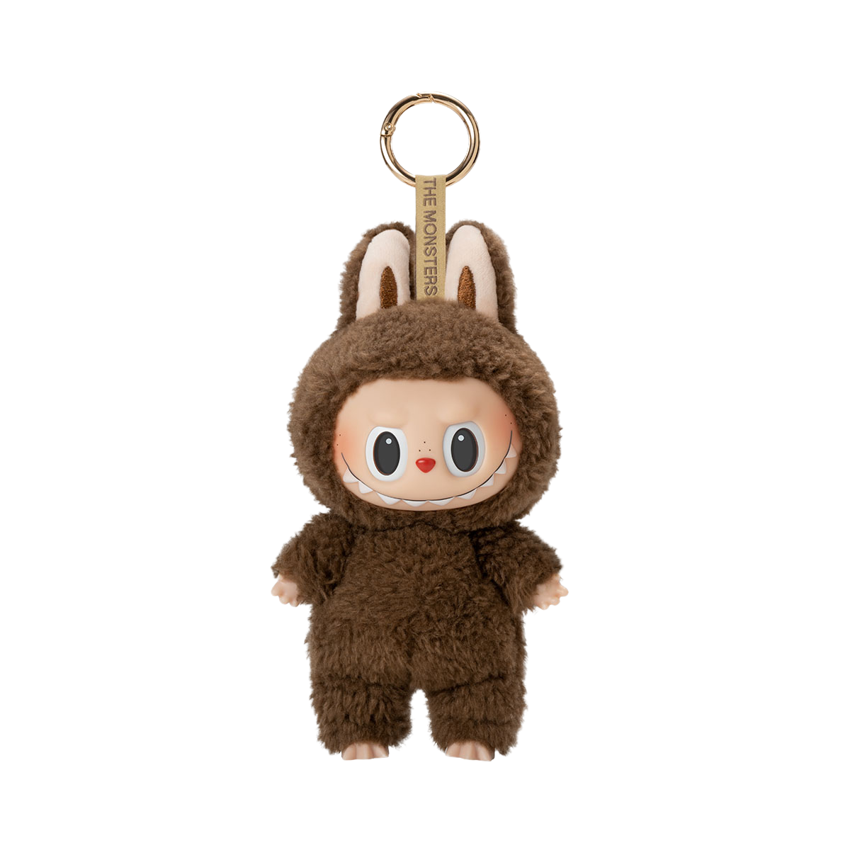 A fluffy dark brown plush toy keychain of a character with a wide, mischievous smile, large black eyes, and bunny ears, with the text "THE MONSTERS" on the keyring strap.