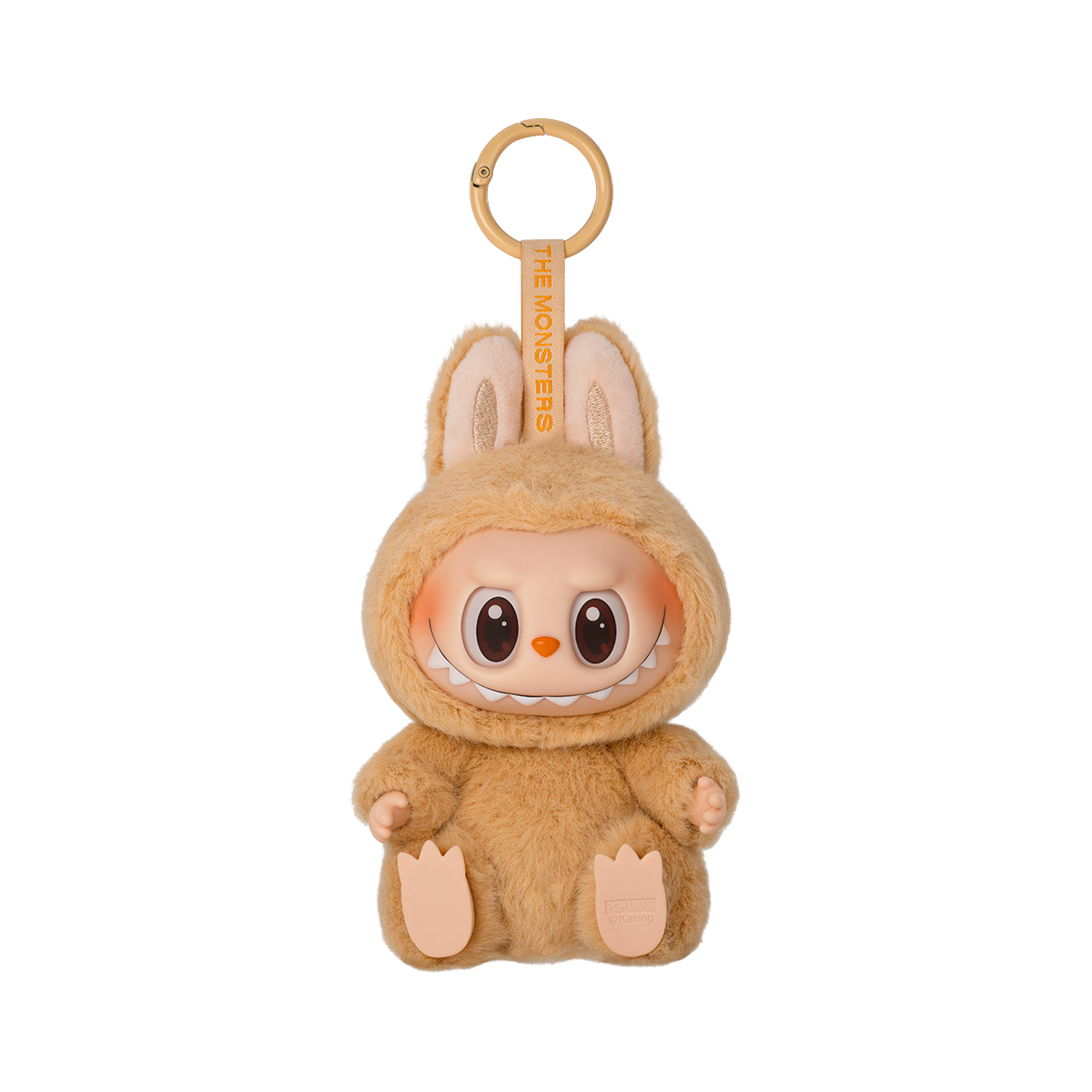 A keychain figure from Pop Mart’s "Have A Seat" Labubu series. The character is dressed in a soft, fluffy light brown-orange bunny suit with tall ears. It has a mischievous expression with eyes open in a joyful smile and a wide, toothy grin. The keychain loop is attached to the top, and a tag reading “THE MONSTERS” is printed on the strap. The figure sits with its feet visible and has a plush texture for added charm.