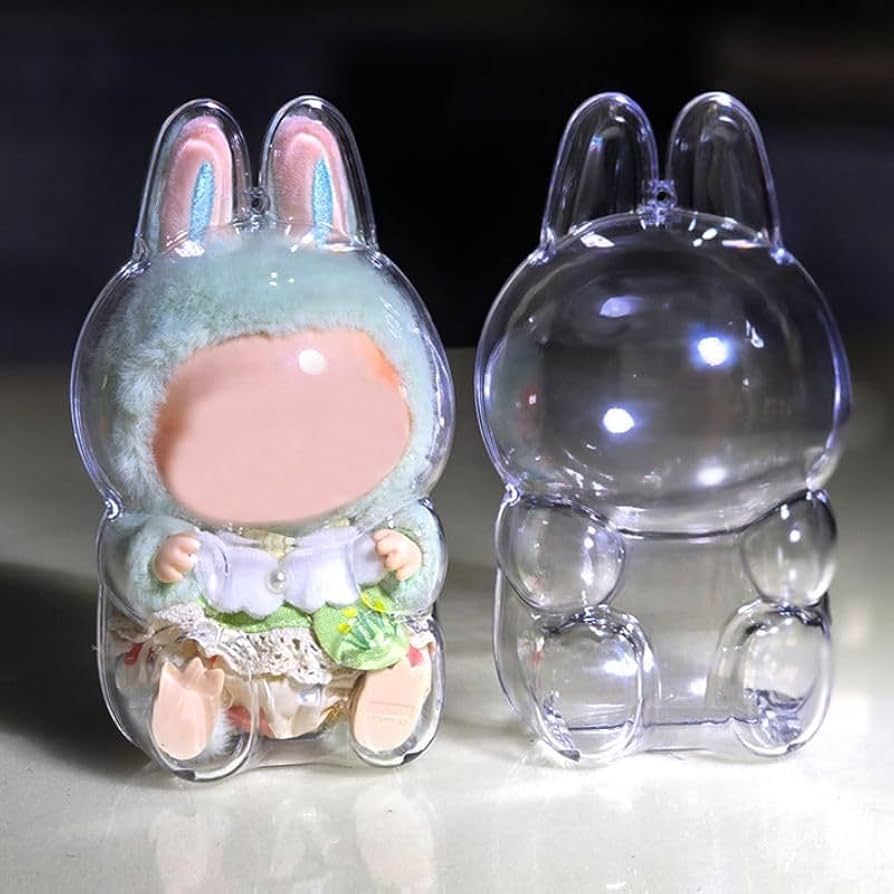 This image features a collectible figure in a soft pastel green bunny outfit encased in a clear protective shell. The case is custom-molded with bunny ears and rounded limbs to perfectly fit and display the plush toy while keeping it secure. Next to it is an empty version of the same bunny-shaped protective case, shown from the back. This setup highlights the protective function of the case while still showcasing the sitting figure inside.